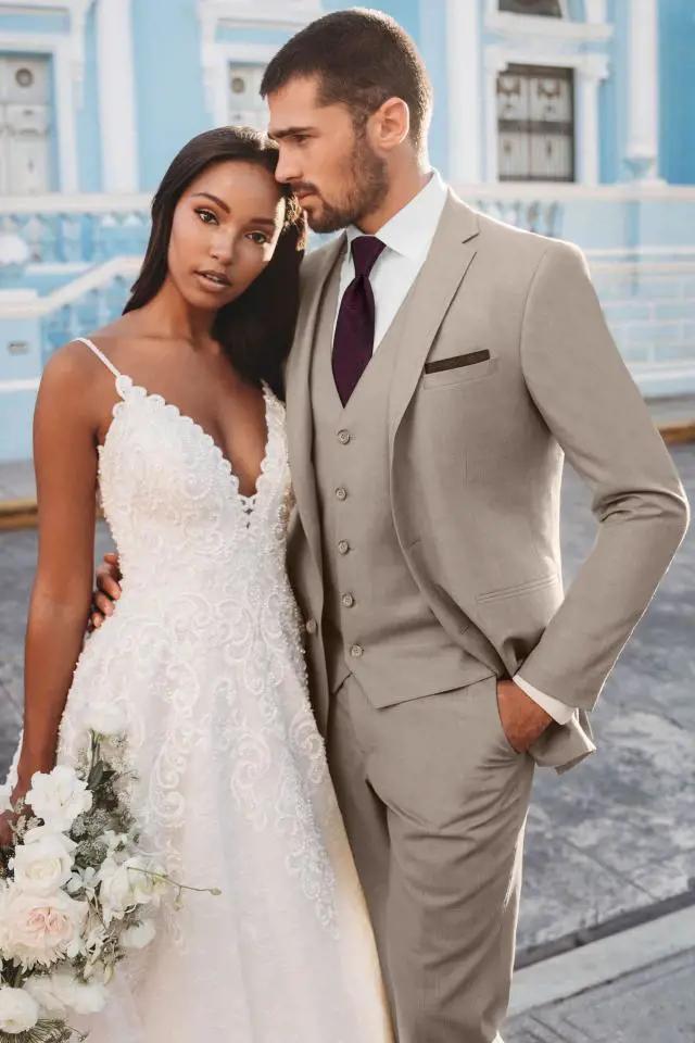 Сouple wearing a white gown and a gray suit. Mobile image